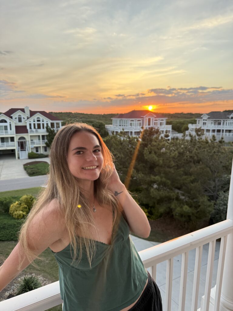 Madison smiling on a balcony with the sun setting behind her