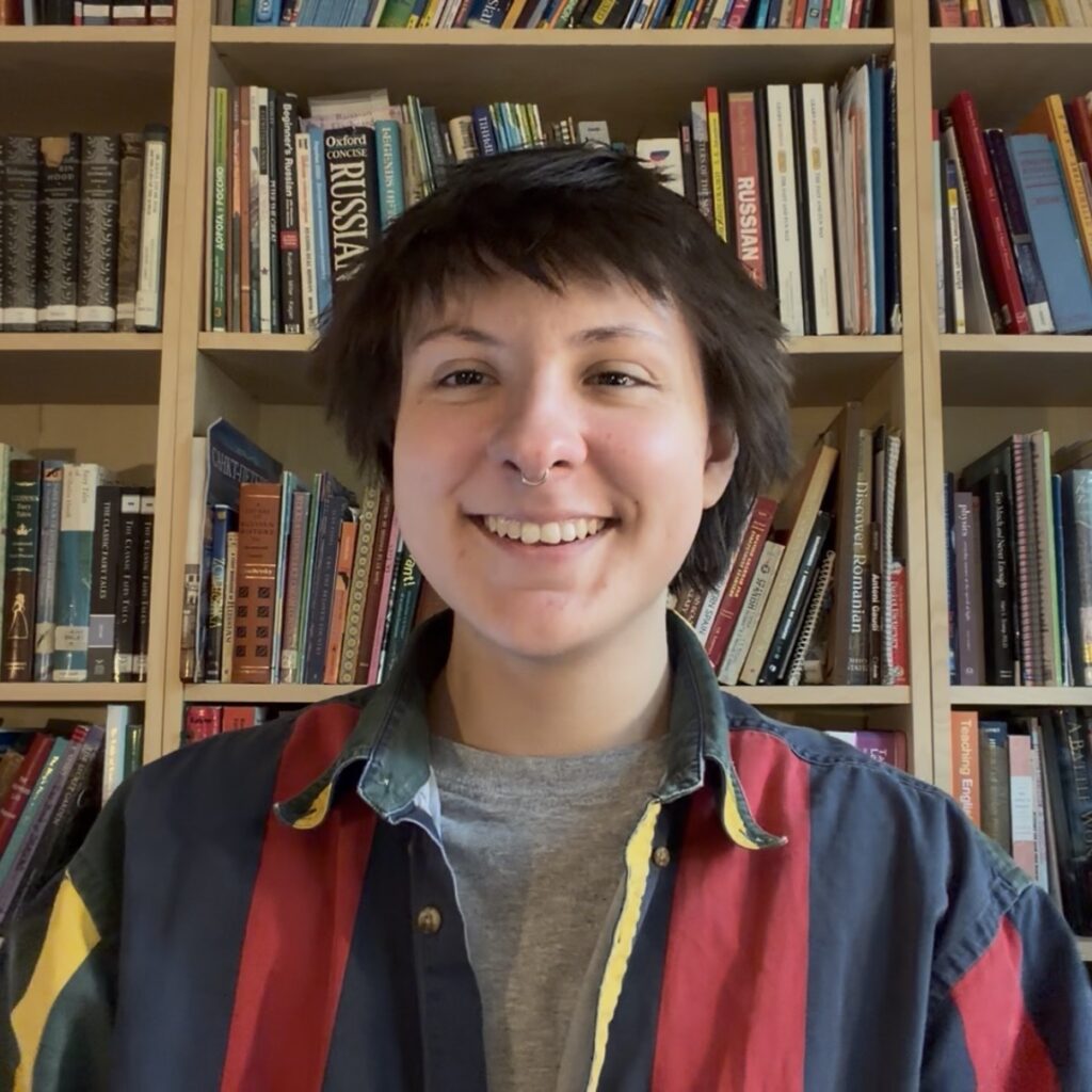 Image of Kelso smiling in front of a bookshelf