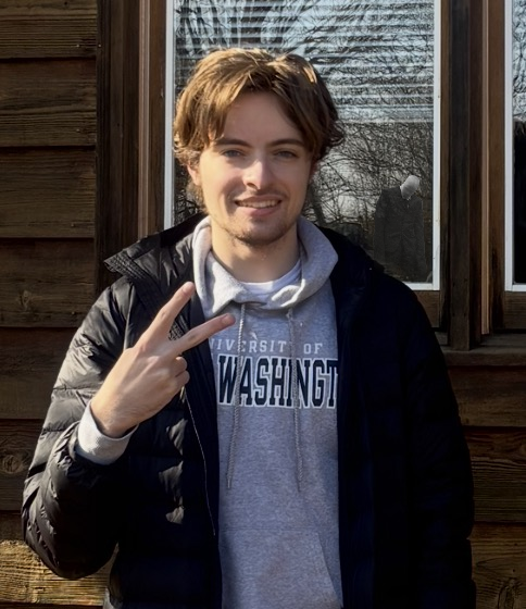 Owen, white guy with blonde hair and a Mary Washington hoodie, in front of a lodge.